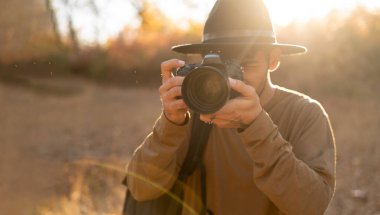 Arap fotoğrafçı dışarıda fotoğraf çekiyor. Kameraya bakarak seyahat ediyor. Doğa Fotoğrafçılığı Konsepti.