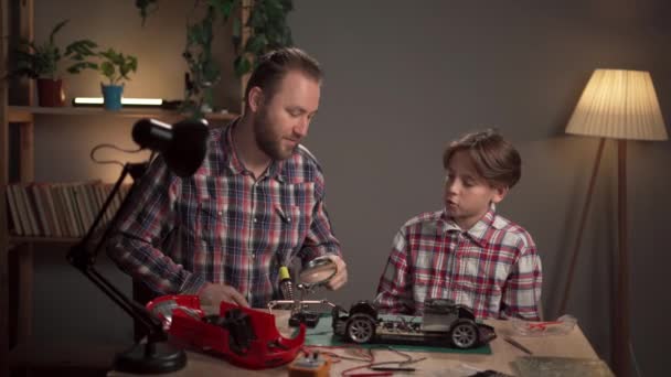 Baba Oğul Evde Lehim Demiri Kullanarak Oyuncak Bir Arabayı Tamir — Stok video