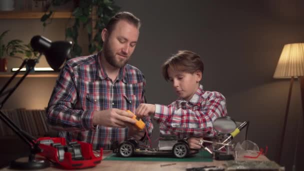 Ojciec Kaukaski Uczy Syna Lutowania Zdalnie Sterowanego Samochodu Domu Mężczyzna — Wideo stockowe