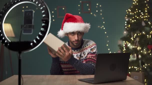 一名阿拉伯男子在家里解拳的同时 用摄像机拍摄视频 男性影响力者向他的订户展示圣诞礼物 博客和社交网络的概念 复制空间 — 图库视频影像