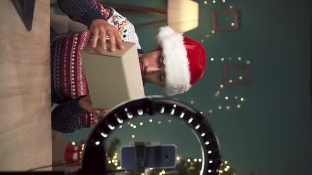 アラブの男性ブロガーは クリスマスのカメラで新しいワイヤレスヘッドフォンで小包を解除し 自宅で彼の技術ブログのビデオを録画します 技術製品レビュー コピースペース — ストック動画
