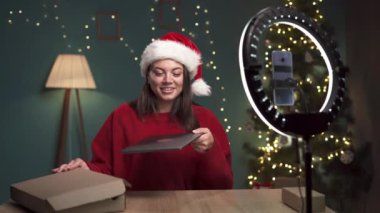 Kadın blogcu, Noel 'de evde dizüstü bilgisayarı açarken modern akıllı telefondan video içeriğini kaydediyor. Nüfuz Edici, modern cihazlar üzerinde inceleme yapıyor. Boşluğu kopyala
