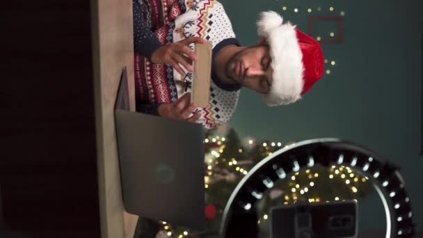 年轻的穆斯林男性博主打开礼品盒 做圣诞礼物和现场直播 用智能手机相机为他的技术博客创建内容的阿拉伯人 垂直录像 — 图库视频影像