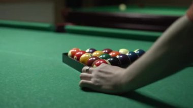 Erkek eller bilardo masasındaki üçgende bilardo toplarını toplar. Amerikan bilardosu. Spor oyunları konsepti.