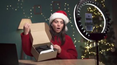 Bir kadın teknoloji ürünü incelemesi yapıyor. Akıllı telefon kamerasında yeni VR gözlüklü kadın vlogger paketi açıyor, Noel arifesinde oturma odasında teknoloji blogu için video kaydediyor. Boşluğu kopyala