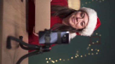 Dijital içerik yaratıcısı, modern cihazları sosyal medyaya açıyor ve inceliyor, kadın etkili ev telefonuyla akıllı telefon için promosyon videosu yapıyor. Noel konsepti
