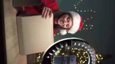 Bayan blogcu Noel 'de şirketlerden hediye paketi açıyor ve canlı yayın yapıyor. İçerik yaratmak için kamera kullanan bir kadın. Dikey video
