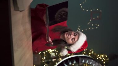Dişi blogcu, akıllı telefon kullanarak dizüstü bilgisayarla paketini açıyor ve evde oturup teknoloji blogu için video içeriği kaydediyor. Bloglama ve Noel konsepti