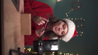 Kadın blogcu sosyal medya etkileyicisi evdeki boks aletinin video incelemesini kaydediyor. Sosyal medya yayını, yeni yıl, Noel konsepti. dikey video