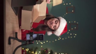Teknoloji Ürünleri İncelemesi. Kadın blogcu yeni kablosuz kulaklıklı bir paketi açıyor ve evdeki teknoloji blogu için bir video kaydediyor. Noel konsepti