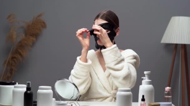 Ung Kvinna Som Applicerar Svart Sheet Face Mask Talar Daglig — Stockvideo