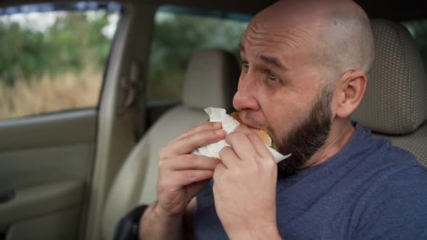 Erkek Sürücü Arabada Otururken Büyük Bir Fast Food Hamburgeri Yiyor — Stok video