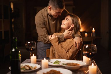 Güzel, tutkulu bir çift mum ışığında romantik bir akşam yemeği yiyip sevgililer gününü evde kutluyor ve öpüşüyorlar. Boşluğu kopyala