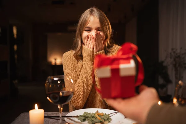 Romantic candlelight dinner for two, Valentine's Day date, authentic couple having dinner with a man giving a gift to a woman, romantic family relationship, Valentine's day celebration concept