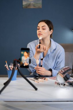 Güzellik blogcusu kadın günlük makyaj malzemelerini kaydediyor. Nüfuz Edici ev stüdyosunda canlı yayın yapan kozmetik ürünleri incelemesi yapıyor. Boşluğu kopyala