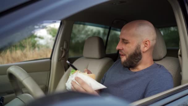 Człowiek Kierowca Jedząc Hamburgera Korzystając Telefonu Komórkowego Samochodzie Niebezpieczne Ryzykować — Wideo stockowe