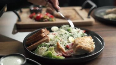 Parmesan peynirli, ev yapımı kızarmış ekmek ve soslu Sezar salatası yiyen bir kadın. Boşluğu kopyala