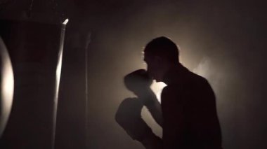 Güç, saldırı ve hareket konsepti. Boksör ve spor salonu geçmişi. Siyah eldivenli bir sporcu. Boks yaparken genç bir adam. Boşluğu kopyala