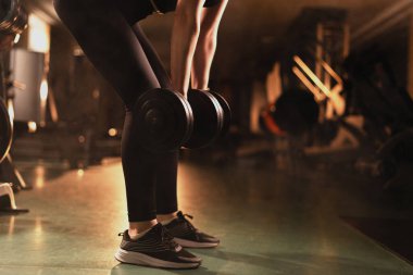 Spor kıyafetli kadın spor salonunda antrenman yapıyor. Dambıl kaldırma egzersizi, sırt güçlendirme. Spor ve spor konsepti. Boşluğu kopyala