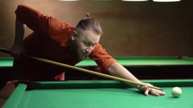 Milenyum erkeği bilardo odasında bilardo masasında bilardo toplarını kovalıyor. Bilardo konsepti. Boşluğu kopyala