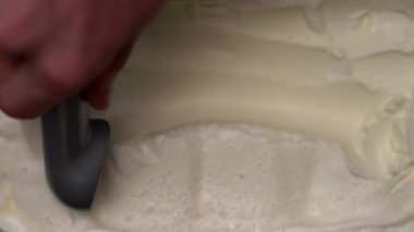 Üst Manzara Paslanmaz çelik kepçeli erkek eli vanilyalı dondurma topluyor. Boşluğu kopyala