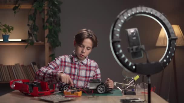 青少年博主在晚上的时候在家里的办公室里焊接汽车玩具 复制空间 — 图库视频影像