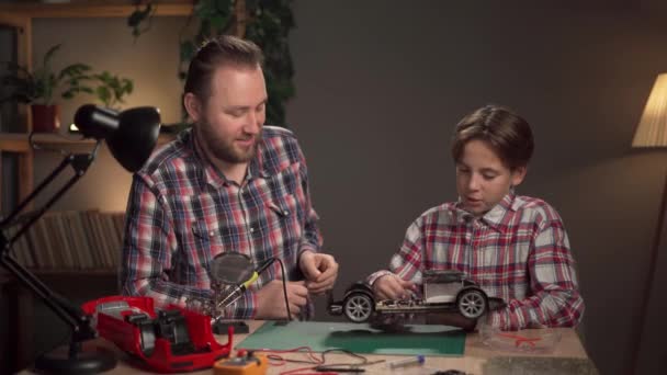修理和焊接玩具车 父亲教儿子修理破损的玩具和设备 复制空间 — 图库视频影像
