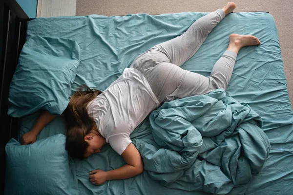 Comfortable pose for sleep. Top view of Young woman sleeping, lying on stomach in bed. Copy space