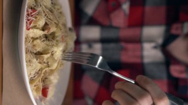 Beyaz adam İtalyan makarnası yer. Parmesan peyniri, et ve domatesle. Gamberini usulü makarna. Çatalın etrafına kaşıkla spagetti dök. Dikey video