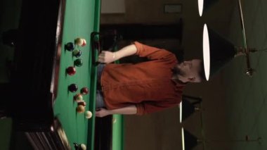 Erkek oyuncu bilardo toplarının renkli piramidini yeşil bilardo masasına bilardo üçgenine yerleştiriyor. Dikey video