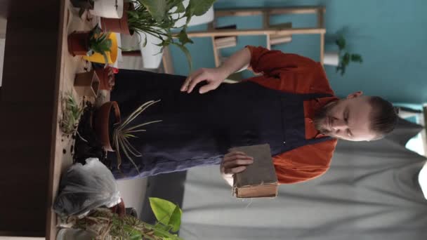 Ελκυστικός Άνθρωπος Βιβλίο Φυτεύει Λουλούδια Γλάστρα Στο Σπίτι Διαβάζοντας Για — Αρχείο Βίντεο