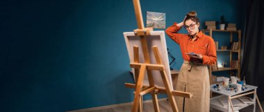 Üzücü ifade konsepti. Brezilyalı genç bir kadın sanatçının atölyesinde kafasını ve ressam paletini tutuyor. Depresyonda ve endişeli, korkmuş ve sinirli. Pankart. Boşluğu kopyala