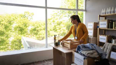 Kadın gönüllü, karton kutularda yiyecek ve giyecek paketleme ve insani yardım veya mülteci yardım merkezinde çalışıyor. Sadaka, bağış ve gönüllülük konsepti. Boşluğu kopyala