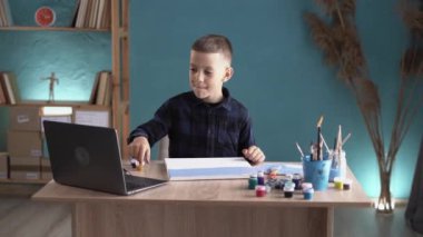 Uzaktan eğitim kavramı. Beyaz çocuk internette resim yapmayı öğreniyor dizüstü bilgisayar kullanıyor. Boşluğu kopyala