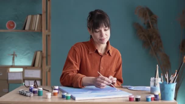 在艺术工作室工作的女艺术家坐在桌旁 面前摆放着其他创作工具和画布 复制空间 — 图库视频影像