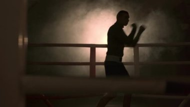 Kickboksör karanlık bir arkaplanda. Arena 'da genç adam kickboks yapıyor. Karışık dövüş sanatları kavramı. Boşluğu kopyala