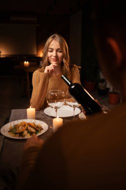 Romantik yemek konsepti. Birbirine aşık genç bir çift şarap içiyor, sevgililer gününü birlikte evde yemek yiyorlar. Boşluğu kopyala