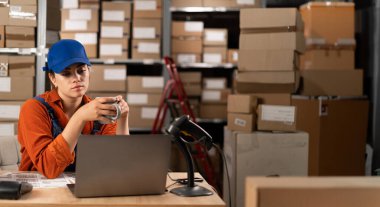 Depo çalışanı çay ya da kahve içiyor depoda sıra sıra paketlerle çalışıyor. Paketler nakliyeye hazır. İşe ara verdim. Boşluğu kopyala