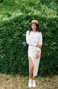 Yaz kıyafetleri içinde, yeşil arka planda gülümseyen zarif genç bir kadın. Boşluğu kopyala