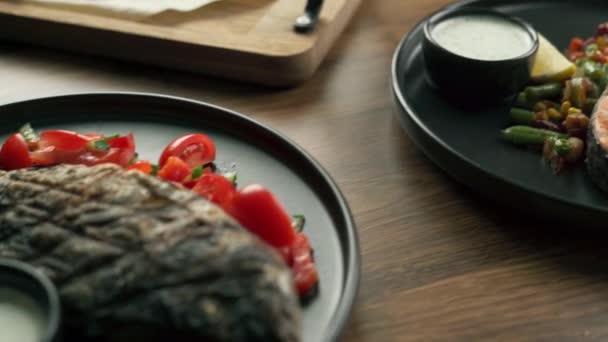 地中海饮食概念 在餐馆里 烤鲑鱼和多拉多鱼放在木制桌子上的黑色盘子里 复制空间 — 图库视频影像