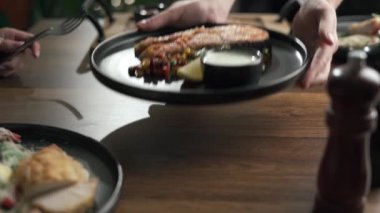 Garson el, kremalı soslu ve salatalı ızgara somon servis ediyor. Boşluğu kopyala