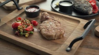 Ahşap masa çeşitli ızgara et, balık ve sebzelerle servis edilir. Tahta kesme tahtalarında kuzu kaburgası. Üst görünüm