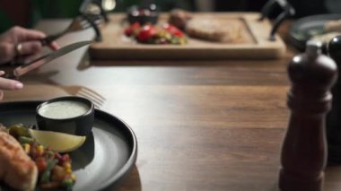 Restoranda bıçak ve çatal kullanarak Sezar salatası yiyen bir kadın zor bir haftadan sonra yemek yiyor. Yakın plan.