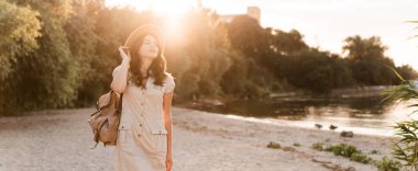 Sırt çantalı bir kadın gün batımıyla birlikte doğada dolaşıyor. Sağlıklı yaşam tarzı ve seyahat konsepti. Pankart. Boşluğu kopyala