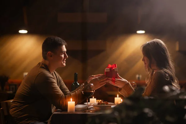 집에서 낭만적 식사를하는 발렌타인 데이를 행복한 사랑하는 남자가 상자를 여자에게 로열티 프리 스톡 사진