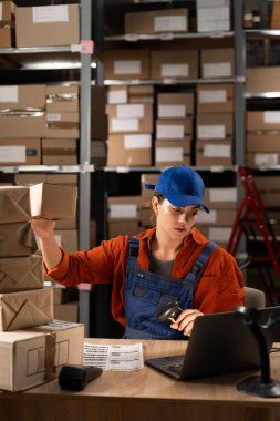 İnternetteki bir mağazanın deposunda siparişleri sıralıyorum. Depo çalışanı dizüstü bilgisayarında lojistik yönetim yazılımıyla çalışıyor. Boşluğu kopyala