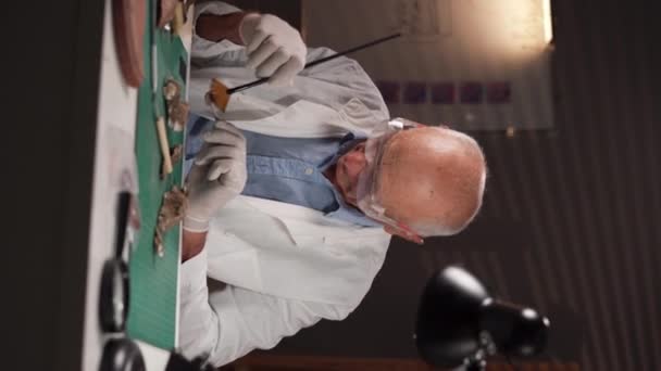 Старый Археолог Мужчина Восстанавливает Древние Монеты Работающие Офисе Поздно Ночью — стоковое видео