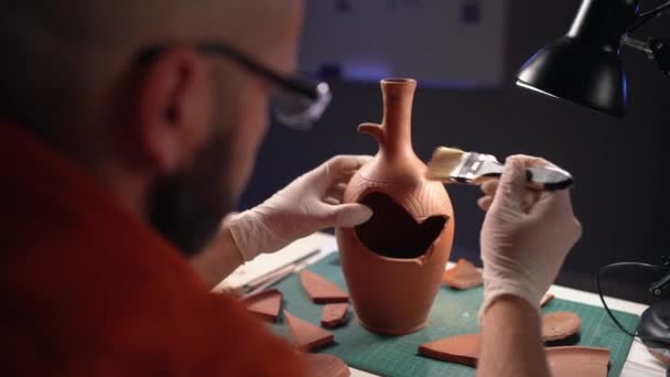 考古学家在办公室工作到深夜 把一个旧花瓶从泥土中清理干净 复制空间 — 图库视频影像