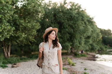 Sırt çantalı güzel genç bir kadın yazın nehirde meditasyon yapıyor. Boşluğu kopyala