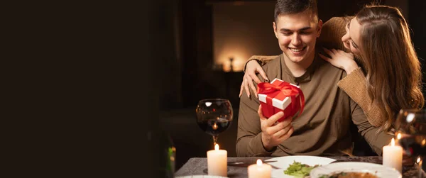 Romantic candlelight dinner for two, Valentine\'s Day date, authentic couple having dinner with a woman giving a gift to a man, romantic family relationship, Valentine\'s day celebration concept